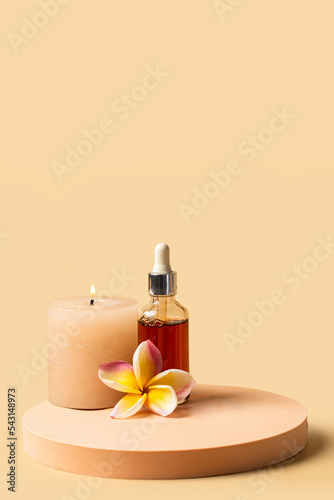 Spa and welness centre concept. Still life composotion with natural dropper bottle  frangipani flower and candle on beige background.