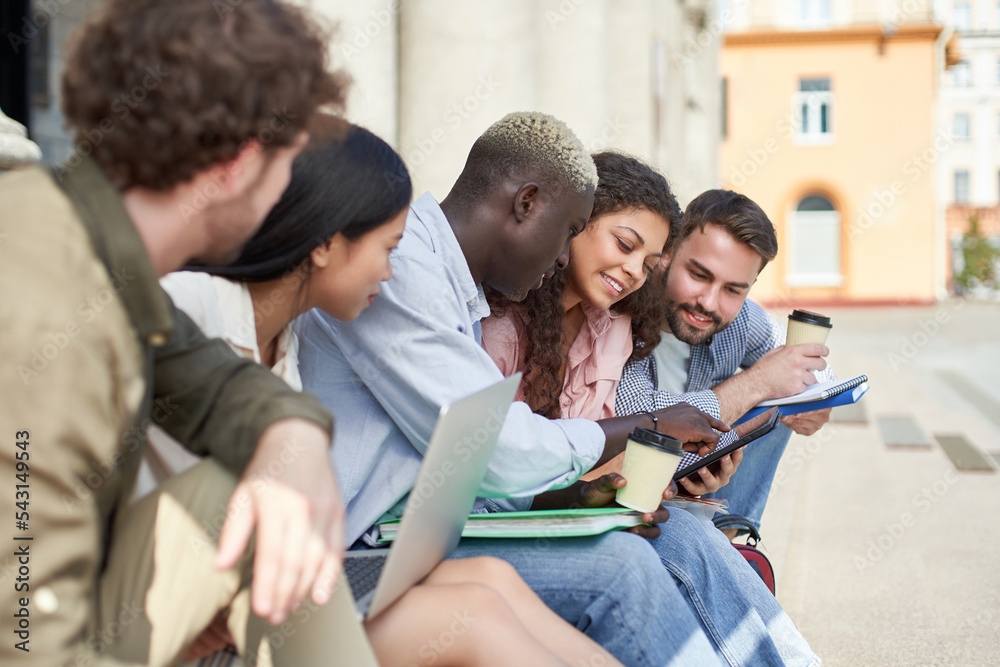 group of students discussing the news sitting on the steps. group of students discussing the news sitting on the steps.