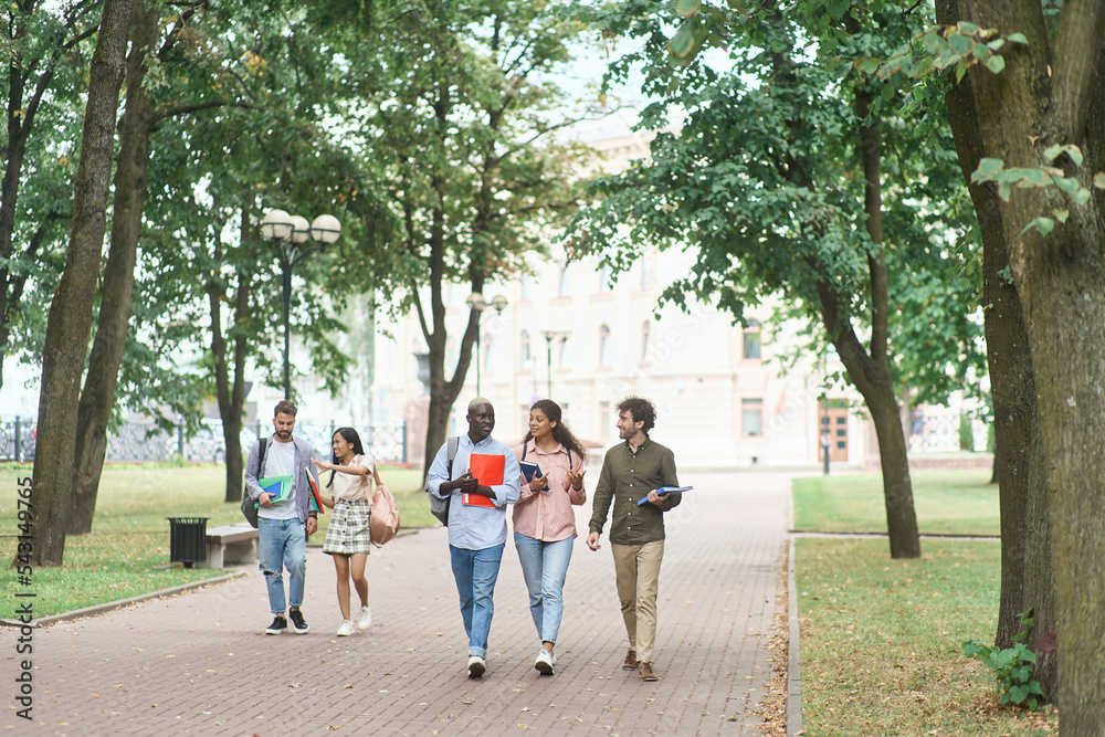 group multicultural students walking together in park.