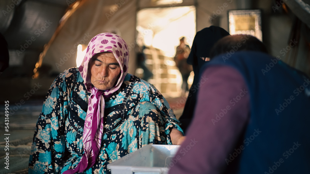 An elderly refugee performs a medical examination inside a makeshift medical tent in the camp.