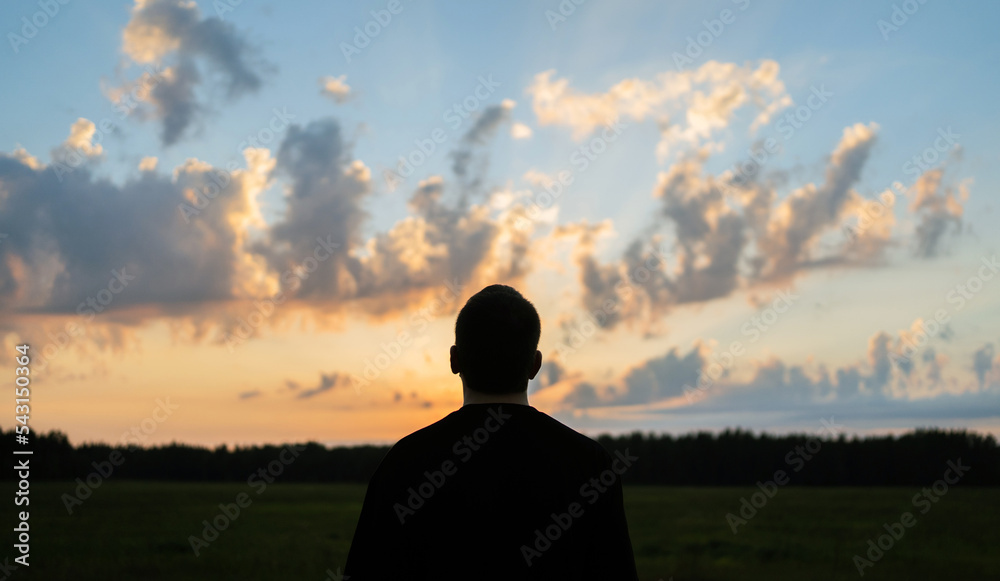 A man in nature looks at the sky and relaxation