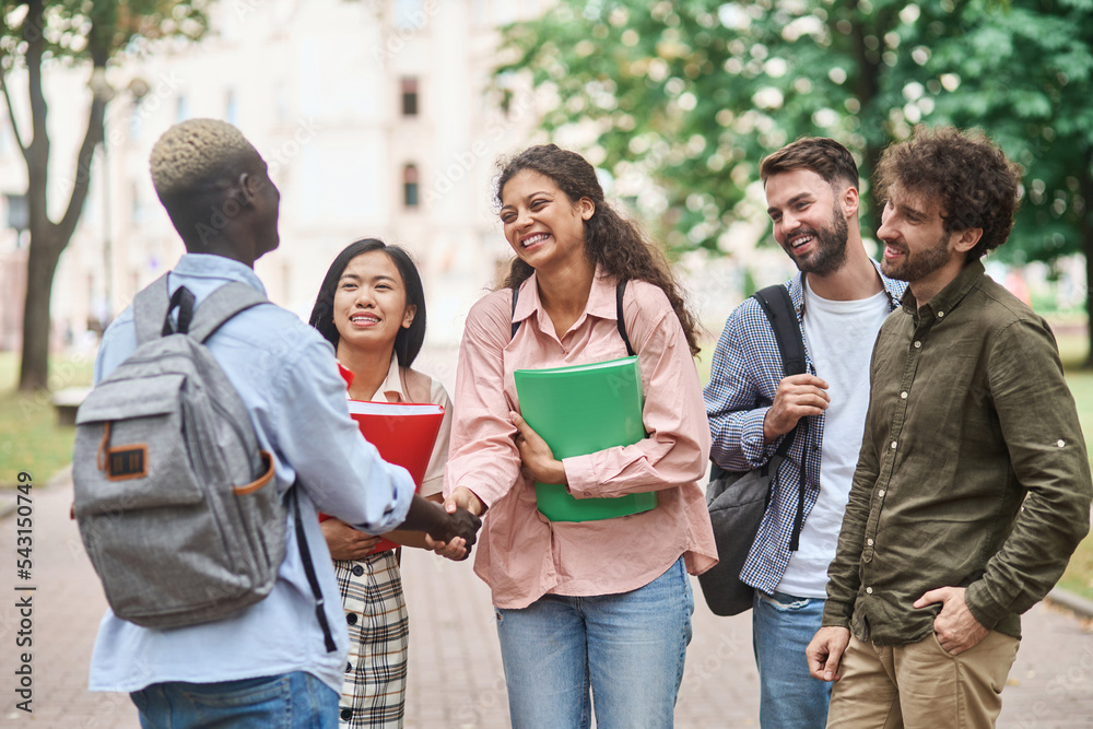 group of students meeting their friend with a handshake.