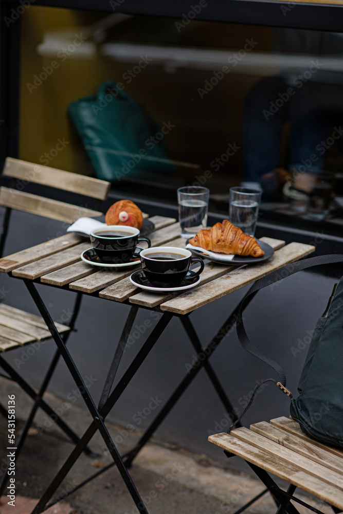 Black coffee with croissants on the table. Aromatic coffee outside. Break to meet a girlfriend. Coffee for two