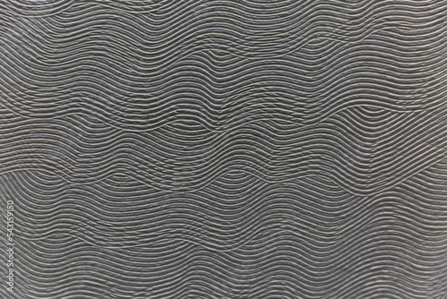 Surface and texture of a gray wave patterned concrete wall. Modern decoration and interior design in loft style. Background. Space for text. Selective focus.