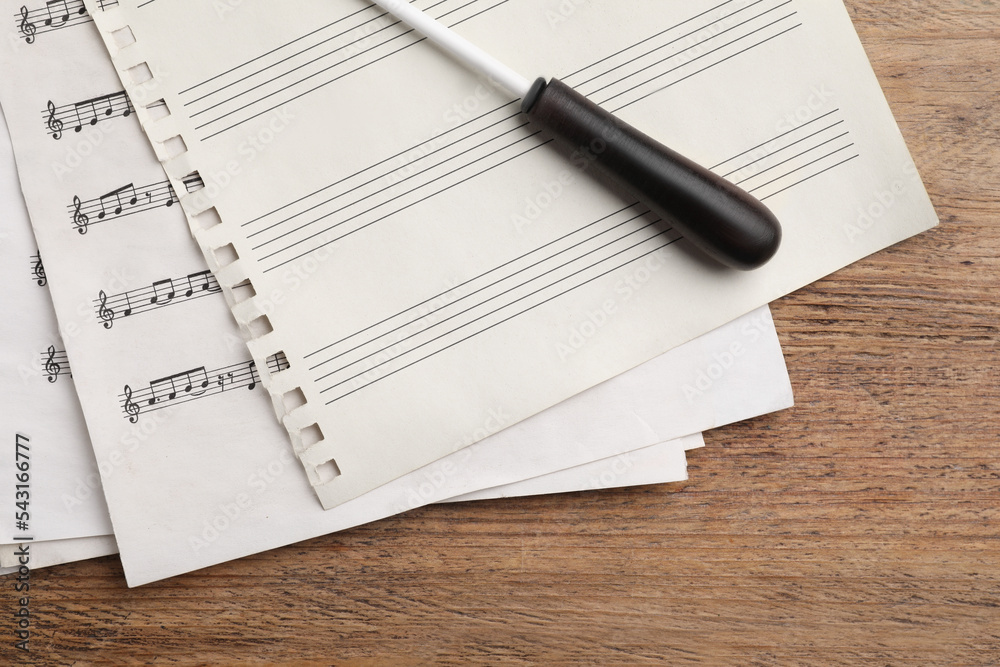 Conductor's baton and sheet music on wooden table, flat lay Conductor's baton and sheet music on wooden table, flat lay