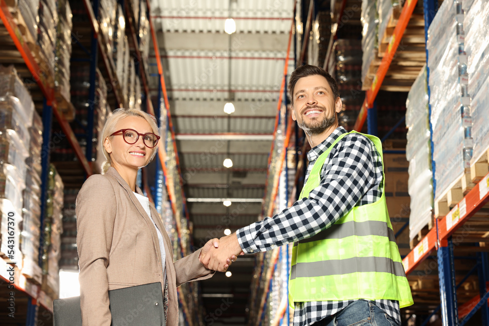 Obraz premium Happy manager shaking hands with worker in warehouse
