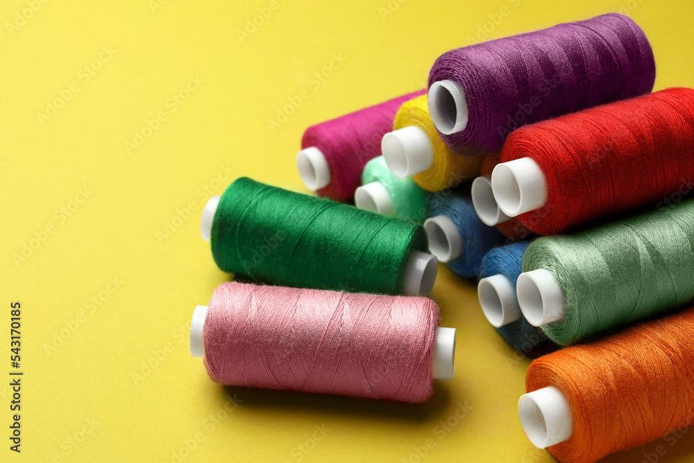Different colorful sewing threads on yellow background Different colorful sewing threads on yellow background