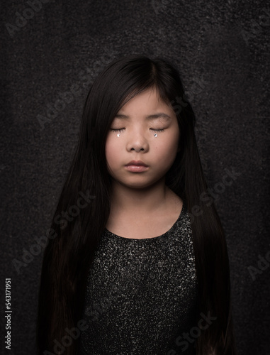 moody fine art painterly portrait of asian girl with silver tear in black dress