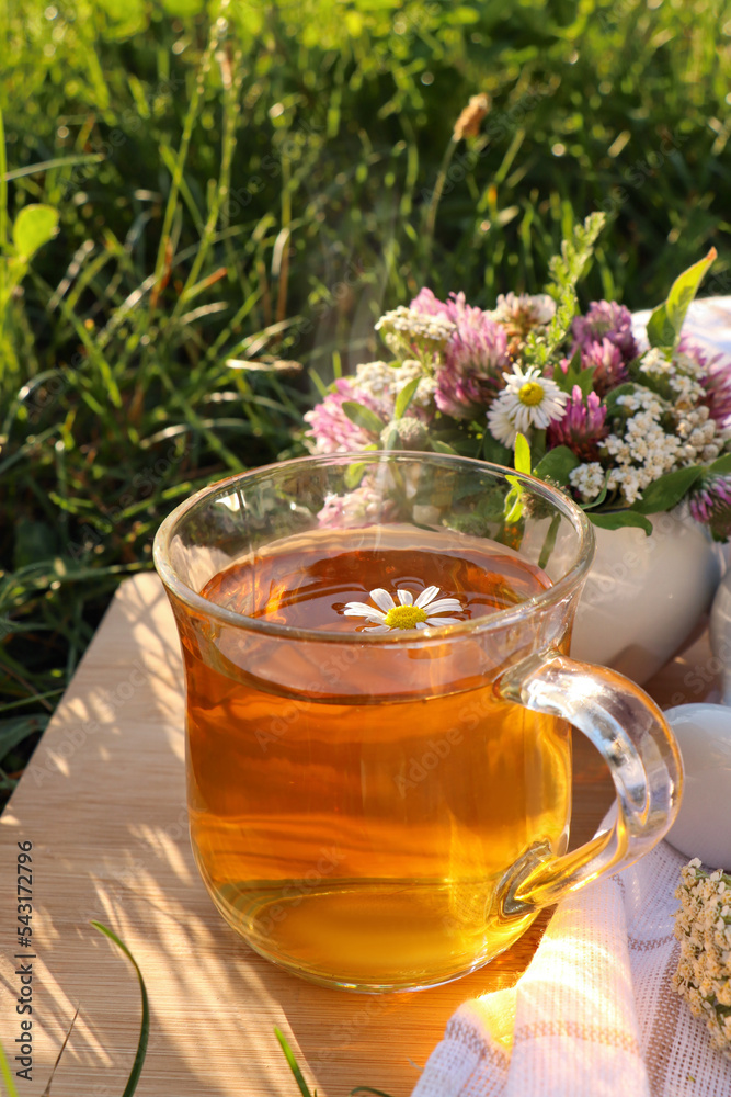 Cup of aromatic herbal tea and ceramic mortar with different wildflowers on wooden board in meadow Cup of aromatic herbal tea and ceramic mortar with different wildflowers on wooden board in meadow