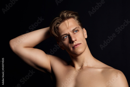 portrait of a serious, preoccupied man posing on a black background without a T-shirt