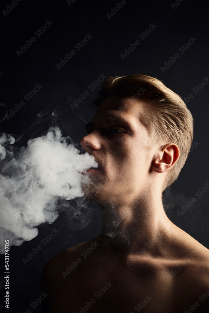 portrait of a smoking man on a black background. Topics of negative habits and bad effects on the body