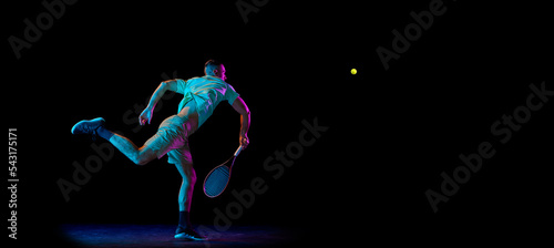 Studio shot of professional tennis player playing tennis isolated over dark background in neon light. Concept of motion, speed, professional sport.