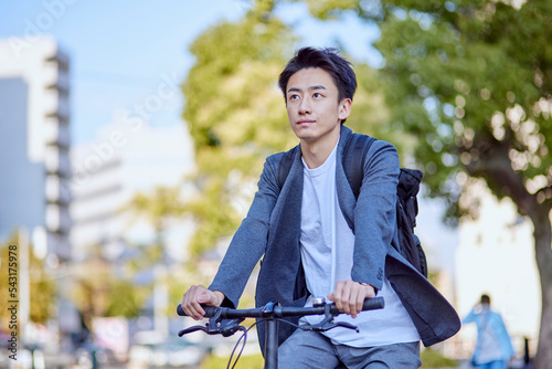 自転車に乗るジャケットを着た若い日本人の男性 photo