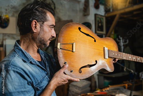 A luthier checks an hollow body guitar neck in his workshop to verify alignment photo