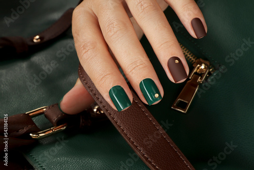 Green brown manicure on short nails with golden dots.