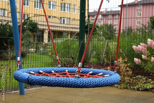 Light blue nest swing on outdoor playground in residential area