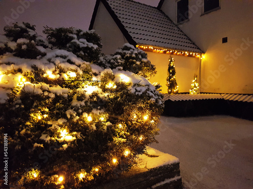 Danish home decorated with christmas lights glowing in the snow outside the house and in the garden in December