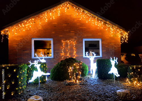 Danish home decorated with christmas lights and ornaments outside the house and in the garden in December