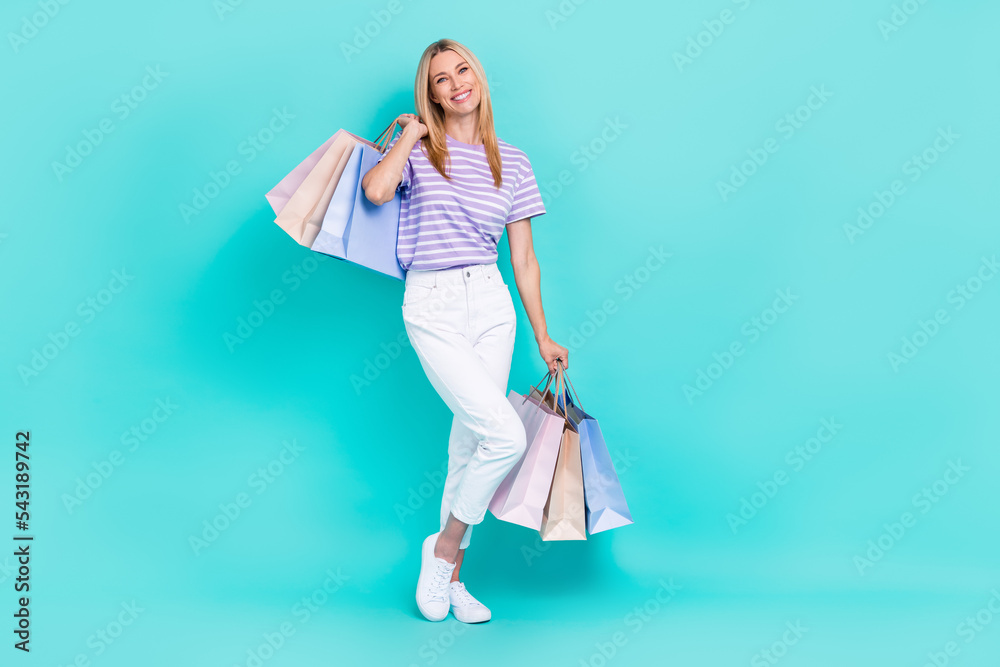 Full length photo of sweet cute lady wear violet striped t-shirt holding bargains empty space isolated teal color background Full length photo of sweet cute lady wear violet striped t-shirt holding bargains empty space isolated teal color background