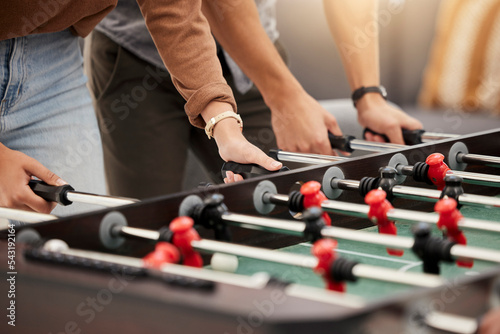 Hands, foosball and table with friends playing a game together indoors for fun or recreation. Football, fun and leisure with a friend group together to play at a party or celebration event