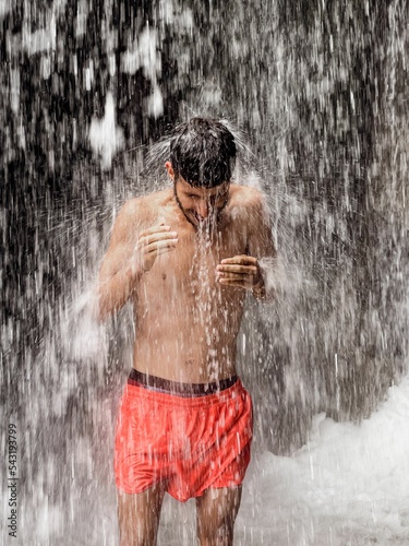 Man standing under a waterfall photo