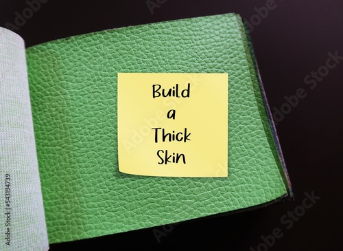 Green articicial PU leather sample with stick note written BUILD A THICK SKIN, self reminder to stop being too sensitive, refuse to get overly responsive to negative comments of others