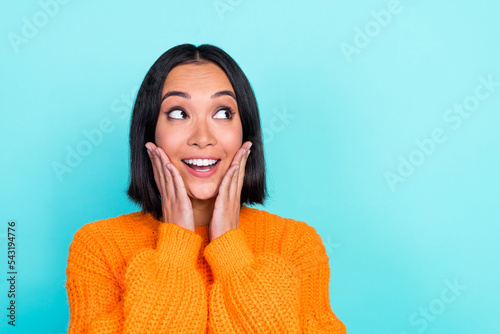 Portrait of positive woman bob hairstyle wear orange sweater look empty space palms on cheekbones isolated on turquoise color background
