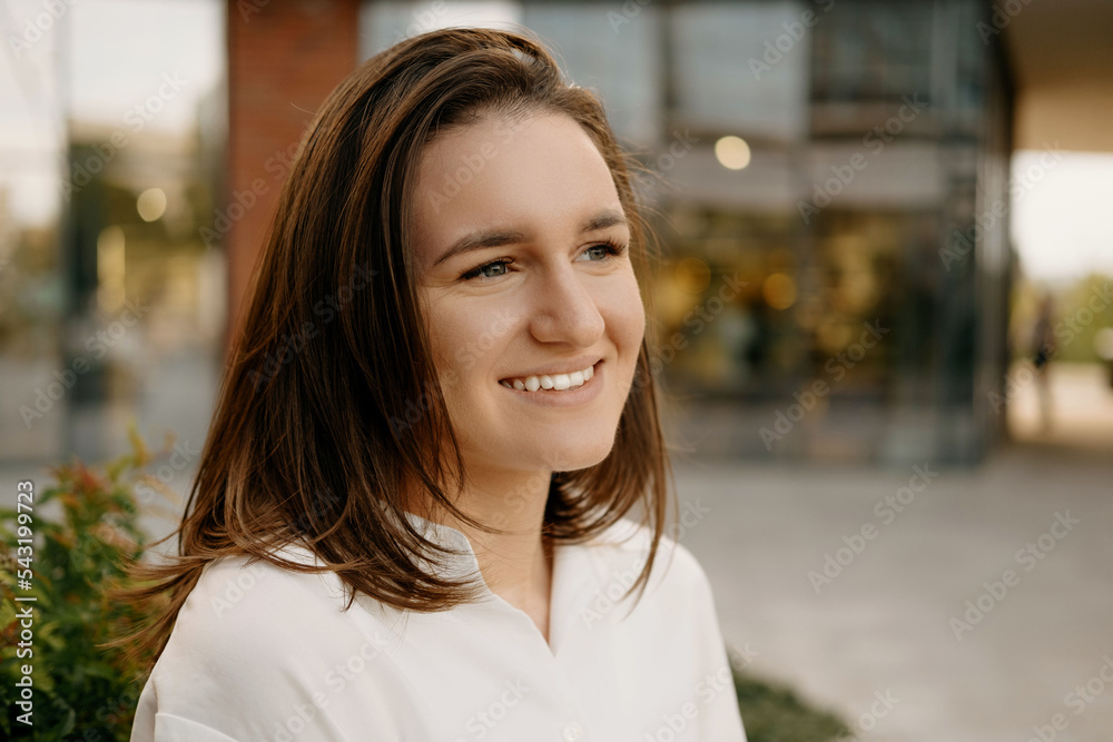 Close up portrait of young beautiful woman looking away over city background.