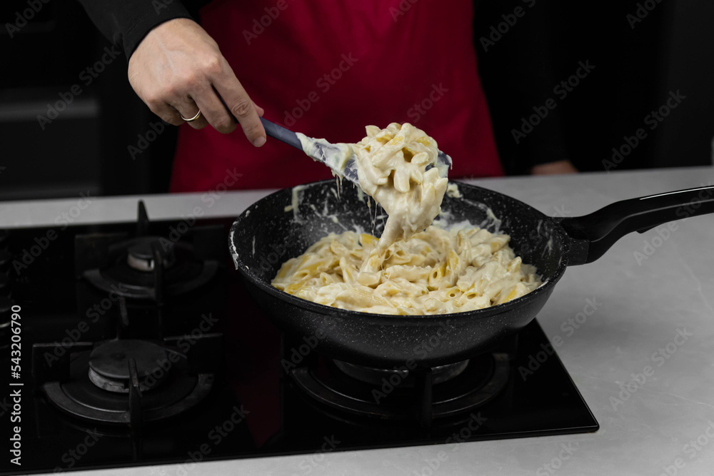 Chef cook making mac and cheese with white cream sauce. Pasta macaroni and liquid yellow cheese. Ingredients: macaroni, milk, cheese, flour, butter. Chef cook making mac and cheese with white cream sauce. Pasta macaroni and liquid yellow cheese. Ingredients: macaroni, milk, cheese, flour, butter.