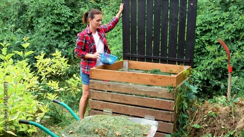 Woman gardener throwing out kitchen waste to the garden compost heap for recycling and fertilizerHigh quality 4k footage