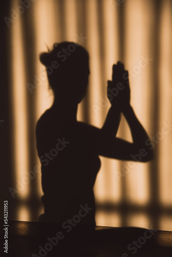 Shadow or silhouette of a woman sitting with her hands together prayer or meditate in suset or sunrise