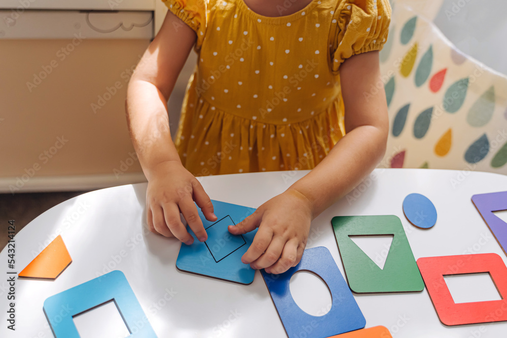 A little girl playing with wooden shape sorter toy on the table in ...