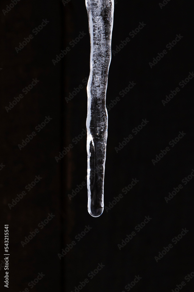 close up of icicle against black wall close up of icicle against black wall