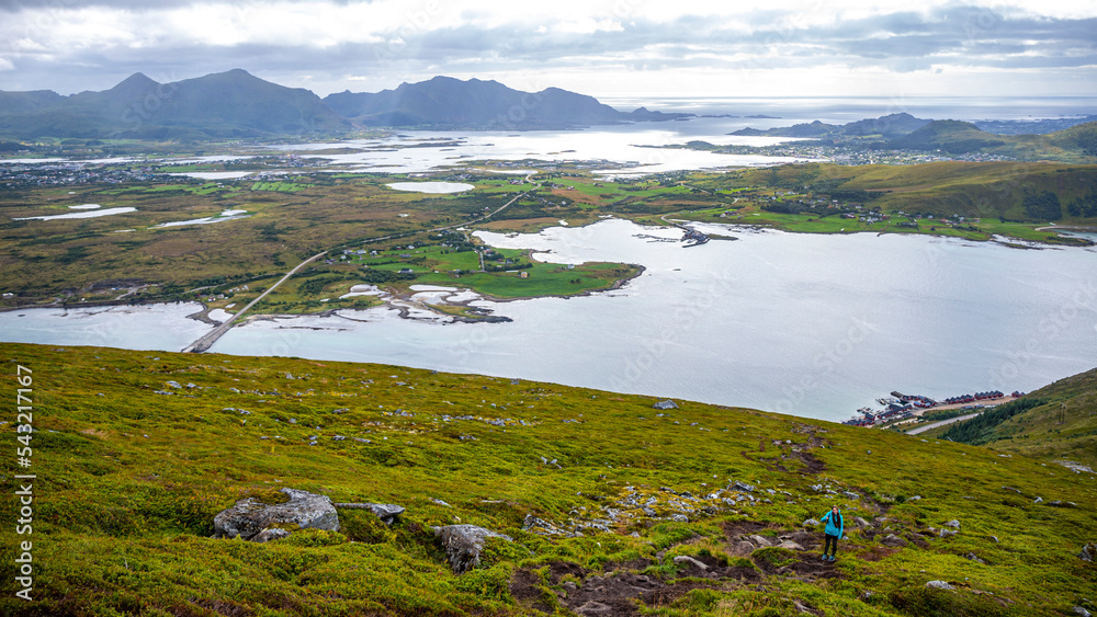 Fototapeta premium girl with backpack hiking Offersøykammen trail head admiring the panorama of lofoten islands, Norway; hiking in the Norwegian fjords