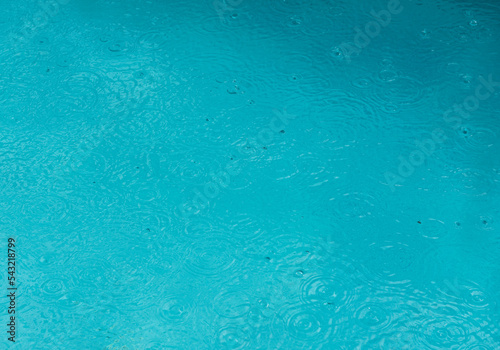 Background of swimming water in a pool with rain drops on the surface covered the ground
