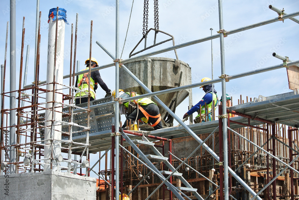 JOHOR, MALAYSIA -MAY 12, 2016: A group of construction workers pouring concrete using concrete bucket into the column form work at the construction site.  