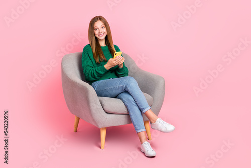 Full length photo of funny cute girl dressed knitted pullover communicating modern gadget empty space isolated pink color background
