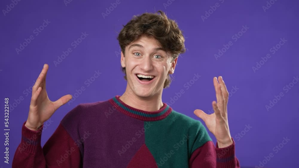 Handsome thinking young man 20s, looks at camera gives mind blown gesture showing explosion of ideas posing on purple background.