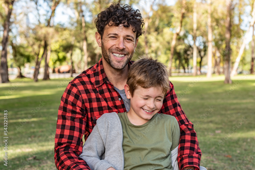 Cheerful dad and son on lawn in park Cheerful dad and son on lawn in park