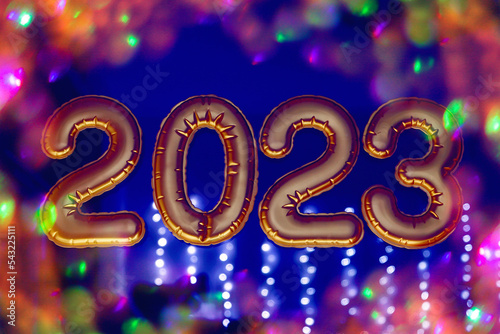 Gold, bronze inflatable foil balloons numbers 2023 on the window against the background of the night city, in neon light. New year 2023, christmas. Celebrating Christmas and New Year 2023.