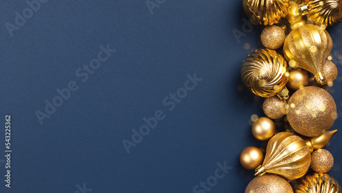 Christmas card with golden glitter balls and toys on blue background with copy space