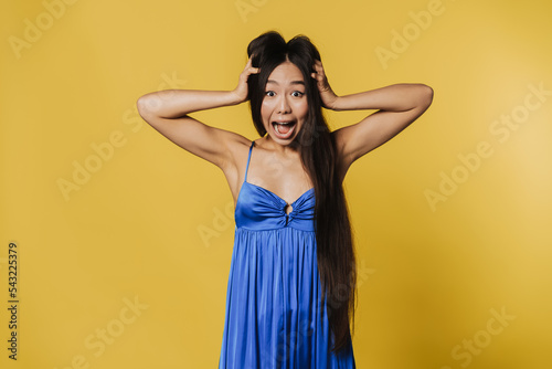 Young asian woman wearing dress screaming and holding her head