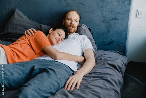 Young white couple hugging while resting on bed at home