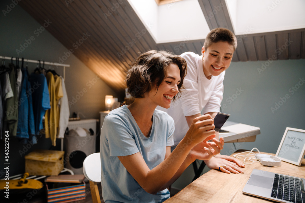 Two lesbian girls holding photo while sitting by desk at home Two lesbian girls holding photo while sitting by desk at home