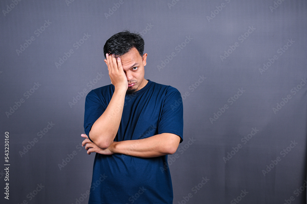 Depressed Asian Young man having stressful time with hands covering face. isolated on gray background.
