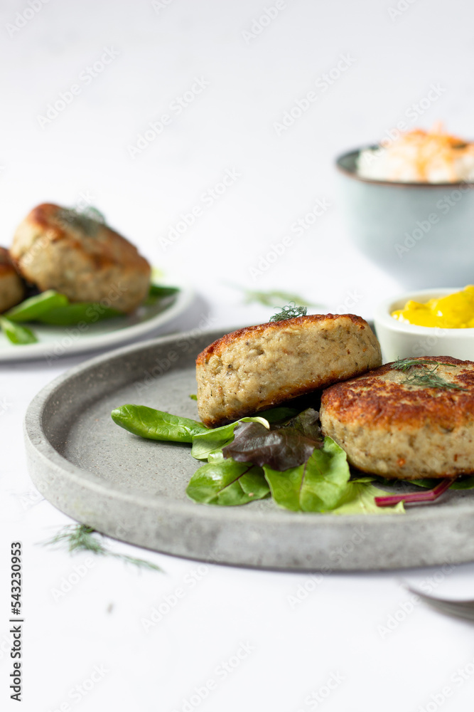 Traditional Iceland fish burgers with mustard curry sauce and some green garnish on a grey tray Traditional Iceland fish burgers with mustard curry sauce and some green garnish on a grey tray