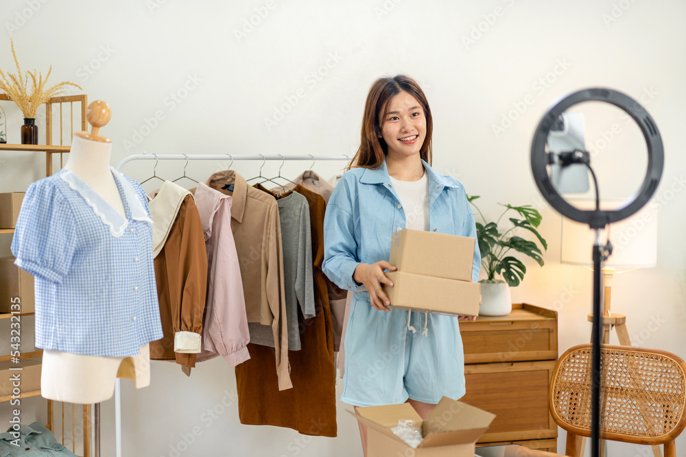 Female online seller is using smartphone to broadcast live on Vlog for introduce fashions and holding Female online seller is using smartphone to broadcast live on Vlog for introduce fashions and holding
