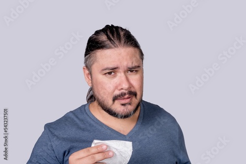 A hurt and emotional man wipes the tears from his eyes with tissue paper. A lonely guy in his 30s crying while being scolded. Isolated on a gray background. photo