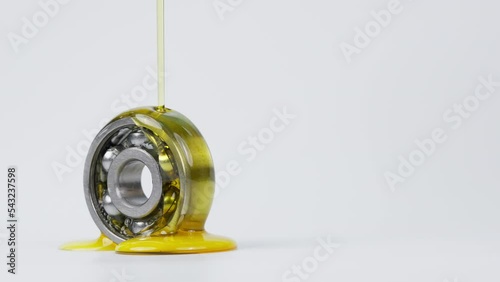 Closed up macro, Pouring automotive engine oil into ball bearing isolated on white background with copy space, engineering and industrial concept. Motor oil on bearing	