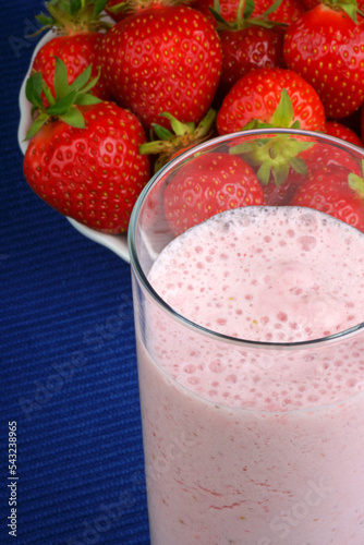 Strawberry milkshake in a glass over a blue background